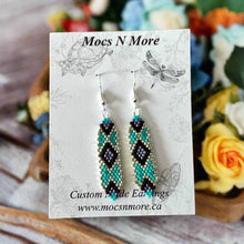 Load image into Gallery viewer, A pair of beaded earrings featuring metallic silver, turquoise, and violet colors with black trim, displayed on a card with the brand name 'Mocs N More' and a dragonfly illustration.