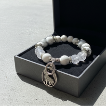 Load image into Gallery viewer, Bracelet with white beads and a lion charm on a black jewelry box.