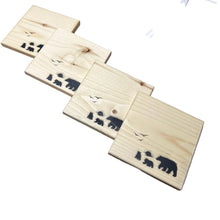Load image into Gallery viewer, wooden coaster with bear prints on a workshop table