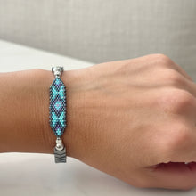 Load image into Gallery viewer, Person wearing a beaded bracelet on a wooden surface with a blurred background