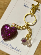 Load image into Gallery viewer, Heart keychain with purple glitter heart charm on a gold chain, displayed on a card.