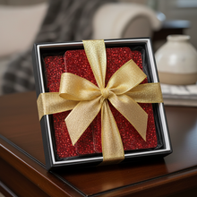 Load image into Gallery viewer, Red gift box with gold ribbon on a wooden surface in a home setting