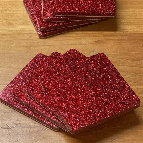 Stack of red glittery coasters on a wooden surface