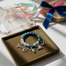 Load image into Gallery viewer, Bracelet with charms on a brown box with ribbons in the background