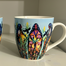 Load image into Gallery viewer, Two mugs with colorful designs of people and nature on a shelf.