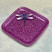 Load image into Gallery viewer, A square, glittery magenta-purple resin tray with rounded corners, featuring a small metallic dragonfly ornament resting on top, set against a neutral light gray background.