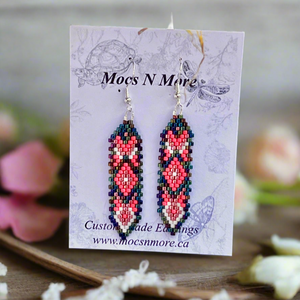 Beaded earrings on a Mocs N More branded card with flowers in the background