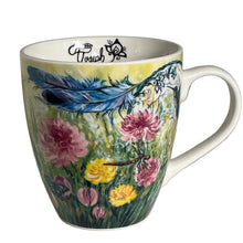 Load image into Gallery viewer, A white ceramic coffee mug decorated with a colorful floral and feather design, featuring pink and yellow flowers, green leaves, and a blue feather on a yellow background. The inside of the mug is white with black script reading 'C'est Joseph'.