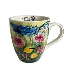 Load image into Gallery viewer, A white ceramic coffee mug with a colorful floral and feather design, sitting on a white shelf.