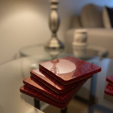 Load image into Gallery viewer, Stack of red glittery coasters on a glass surface with a blurred background