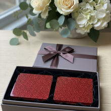 Load image into Gallery viewer, Red glittery square boxes in a gray box with a brown bow, placed on a light surface with flowers in the background.