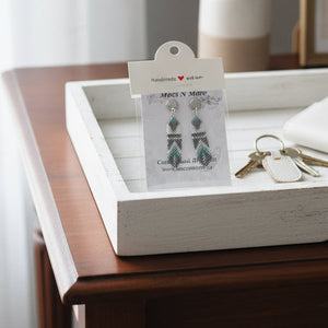 Wooden tray with jewelry card, keys, and wallet on a wooden surface.