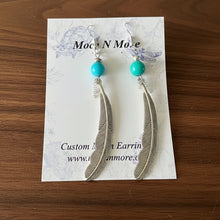 Load image into Gallery viewer, Feather earrings with turquoise beads on a display card against a wooden background
