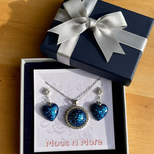 Load image into Gallery viewer, Jewelry set with blue heart-shaped pendants on a &#39;Mocs N More&#39; card.
