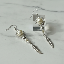 Load image into Gallery viewer, Pearl flower and feather earrings close-up on marble