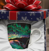 Load image into Gallery viewer, Decorative mug with a scenic design in a gift box with a red ribbon, set against a warm fireplace background.